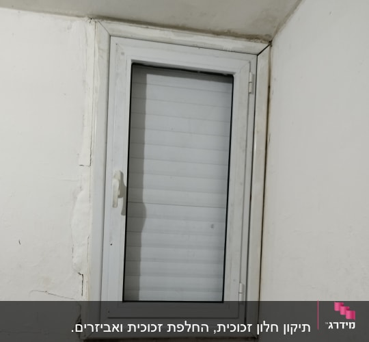חלון עם תריסים סגורים במסגרת לבנה